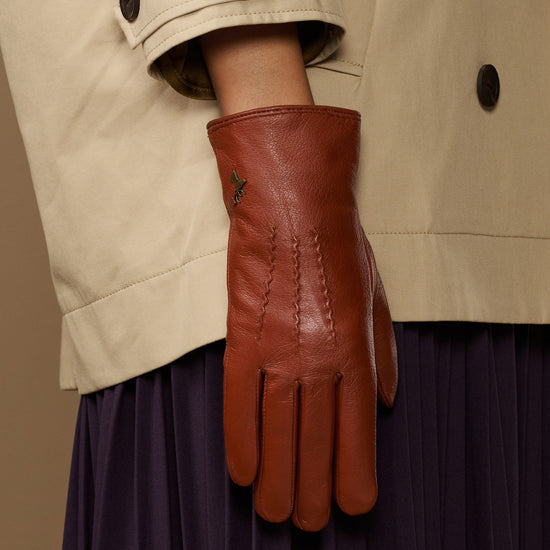 Cognac brown leather glove close-up with small embroidered motif on back