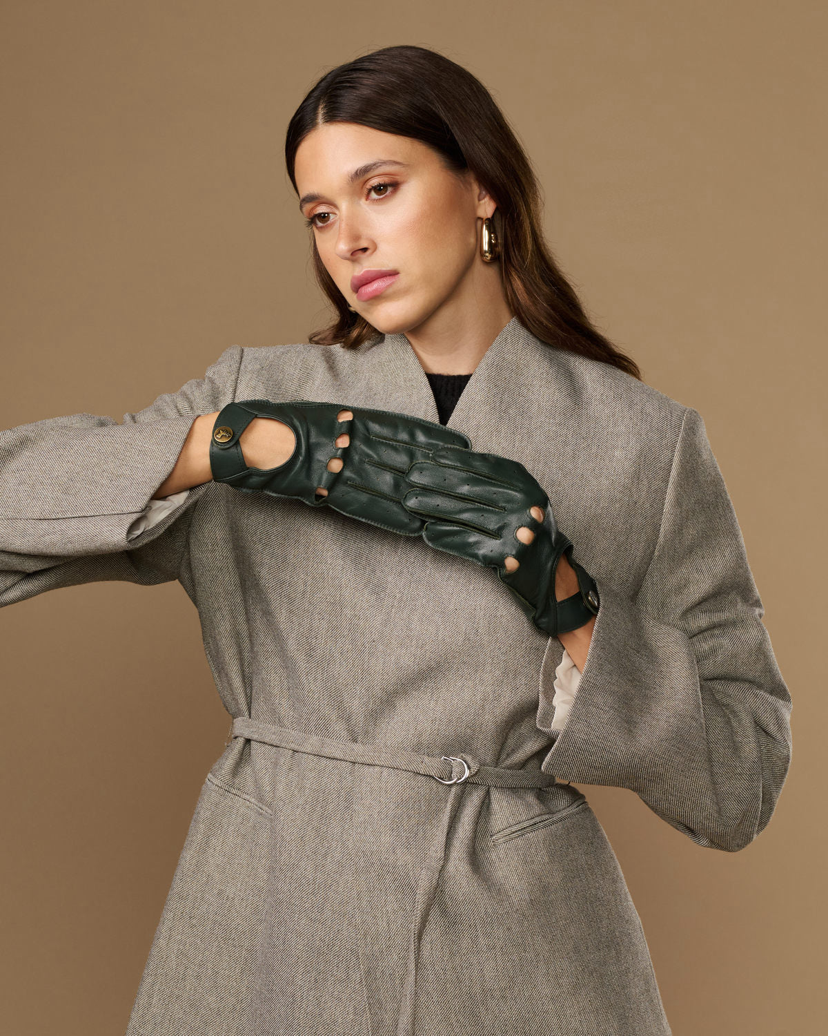 Dark green leather driving gloves with studded cutout design and round gold marks