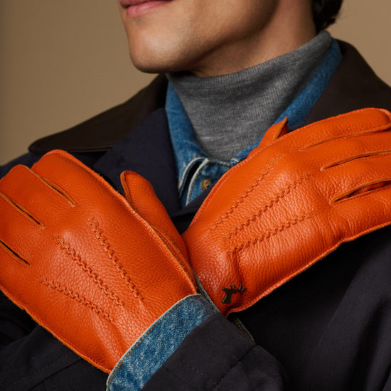 Orange leather gloves with blue cuff lining, close-up on joined hands