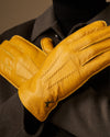 Yellow leather gloves held up close-up, visible stitched seams and texture