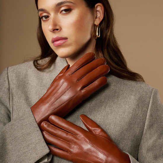 Extra-long cognac leather gloves with rabbit-fur cuffs, layered close-up