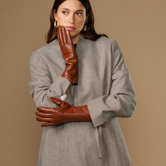 Extra-long cognac leather gloves with fur-lined cuffs, worn