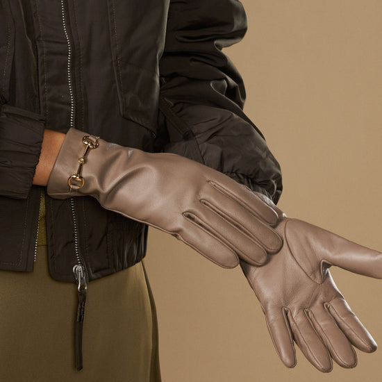 Taupe leather glove close-up with gold-tone buckle wrist strap and stitching lines