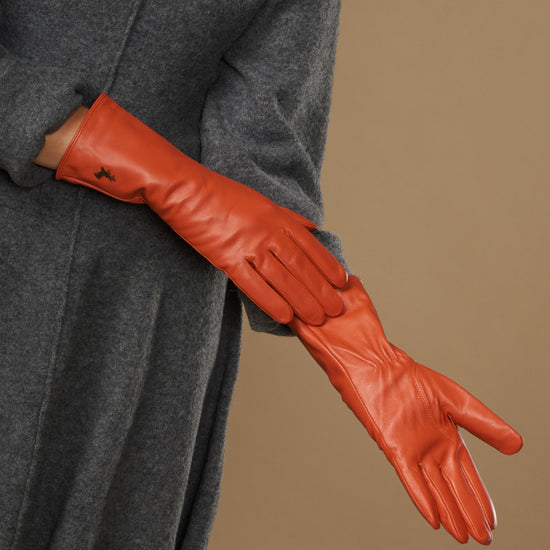 Orange long leather glove laid over sleeve, showing stitched finger panels