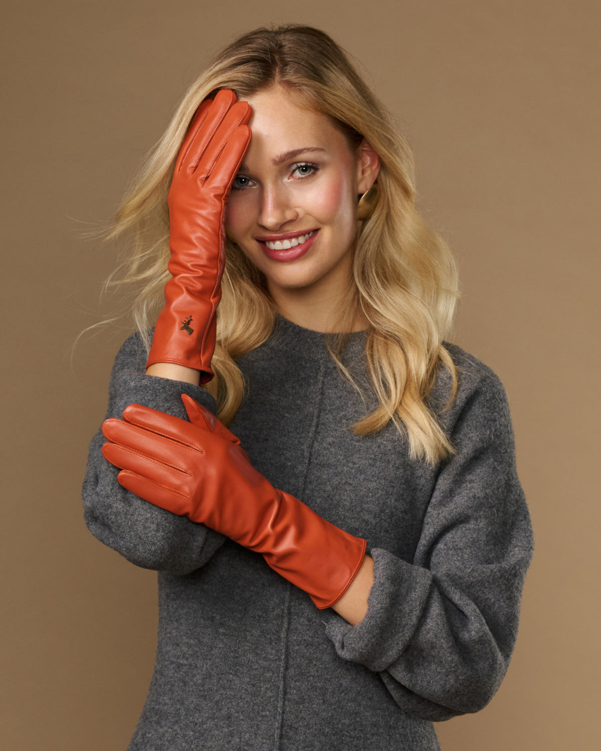 Orange leather gloves worn near face, long cuffs visible with finger stitching