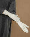 White leather gloves, side view with logo on cuff and smooth, fitted finish
