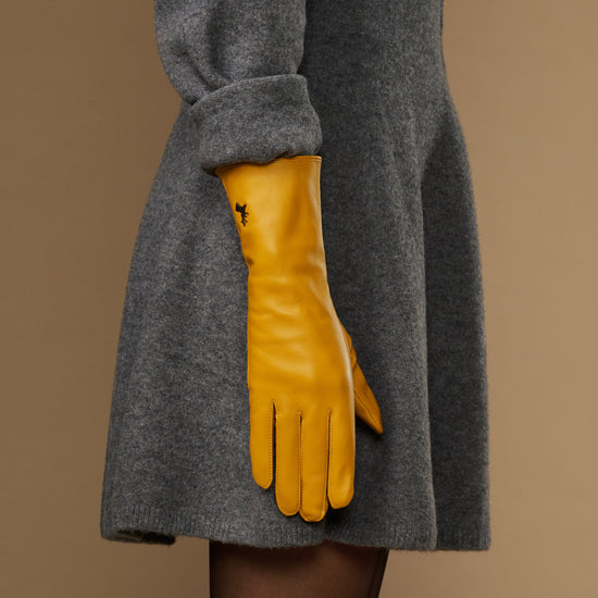 Yellow extra-long leather glove paired with matching cuff logo; finger tips angled down