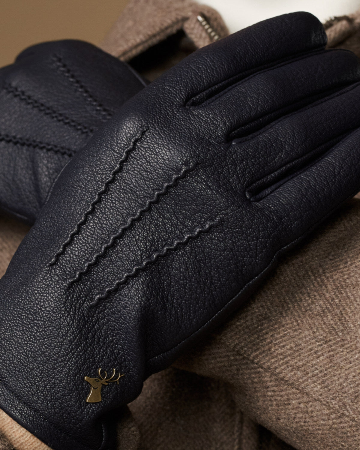 Men's navy leather gloves with wool lining, gold logo and detailed textured stitching