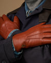Men's cognac leather glove close-up with blue cuff lining and stitched seams