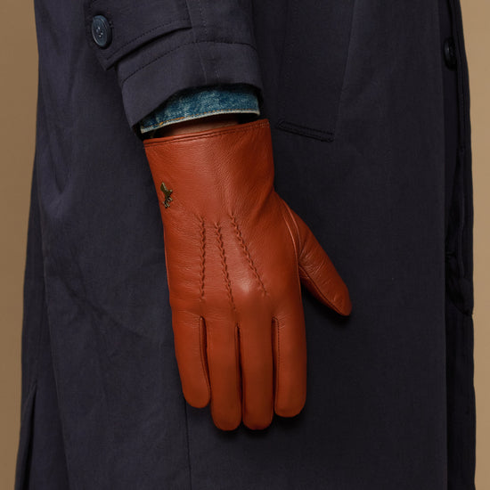 Men's cognac goatskin glove on navy coat sleeve, blue lambswool lining