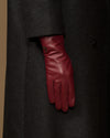 Bordeaux leather glove showing from a dark coat sleeve with stitched cuff
