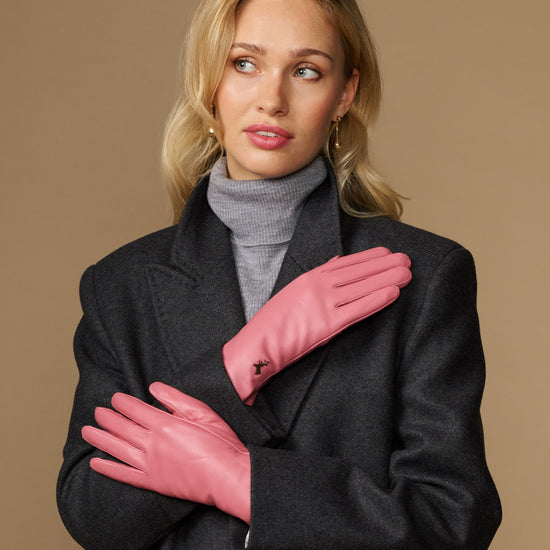 Women’s pink leather gloves crossed at chest, with small logo on the back