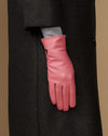 Women’s pink leather glove on a coat sleeve, showing wrist seam and finger stitching