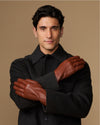 Cognac leather gloves with fleece-lined cuffs, arms crossed with gloves on