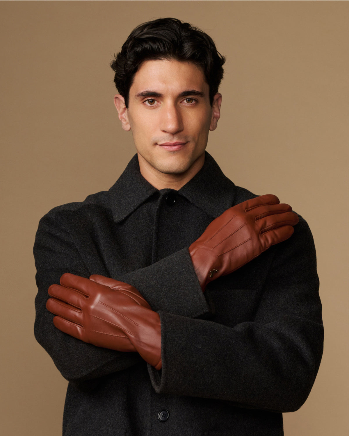 Cognac leather gloves with fleece-lined cuffs, arms crossed with gloves on