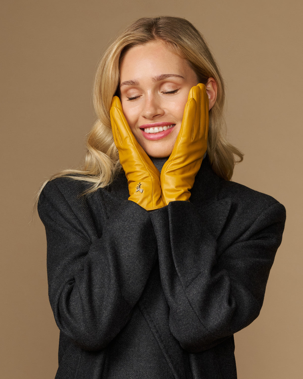 Yellow leather gloves worn on both hands with stitched fingers and snug wrist cuffs