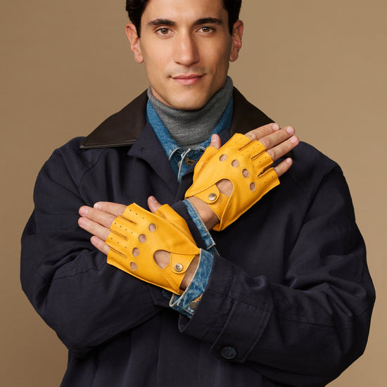 Yellow fingerless driving gloves held together, perforated knuckle details