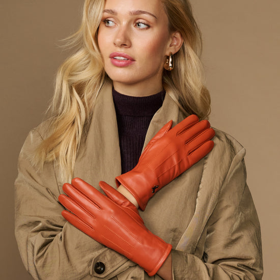 Orange sheepskin leather gloves with warm fleece lining, held together at chest