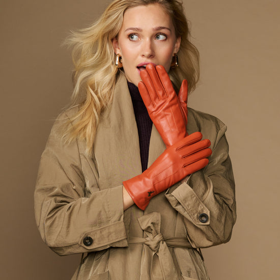 Orange leather gloves with fleece lining, one glove resting against the other
