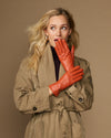 Orange leather gloves with fleece lining, one glove resting against the other