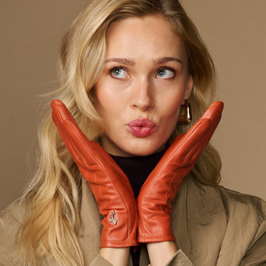 Orange leather gloves with fleece lining, hands together under chin