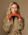 Orange sheepskin leather gloves with fleece lining, worn with arms crossed at chest