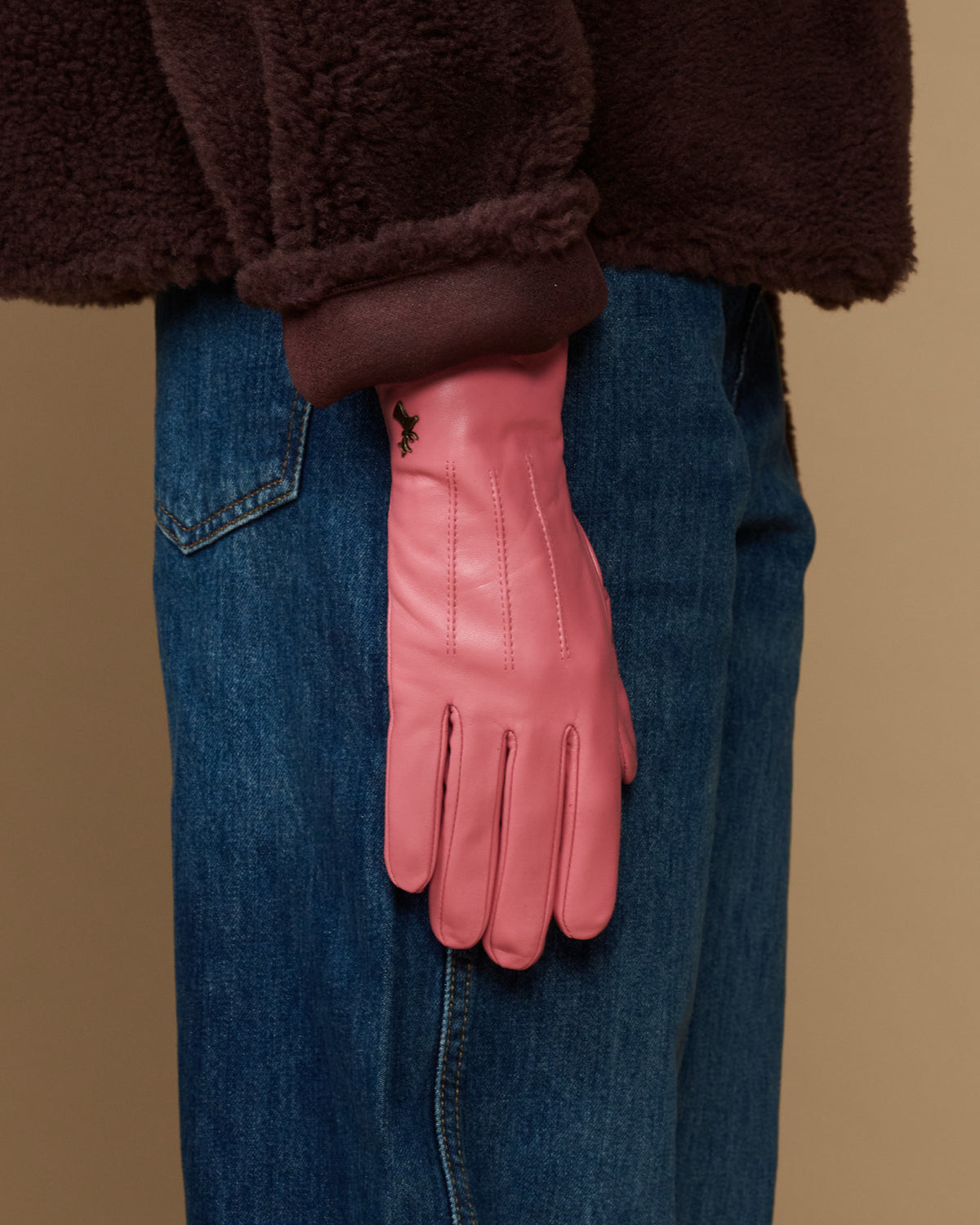 Pink leather glove worn with denim jeans, dark fleece lining at cuff