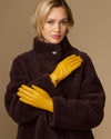 Yellow sheepskin leather gloves with dark fleece lining, worn with a plush coat