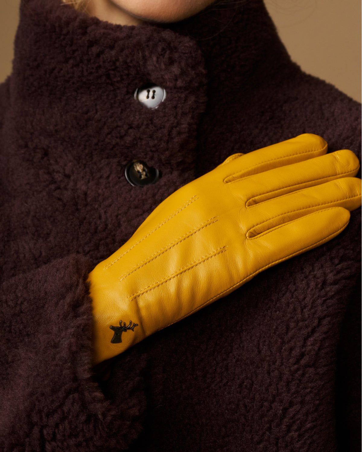 Yellow leather glove detail with stitched paneling and dark fleece collar