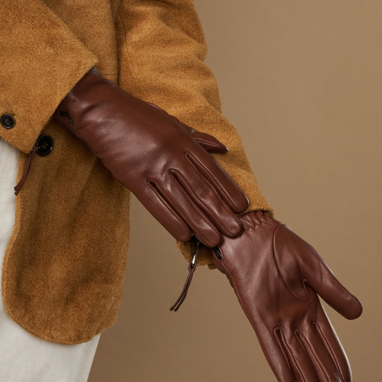 Close-up of brown leather gloves showing stitched seams and side zip