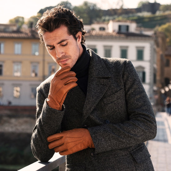 Man wearing cognac brown peccary leather gloves with cashmere-lined cuffs