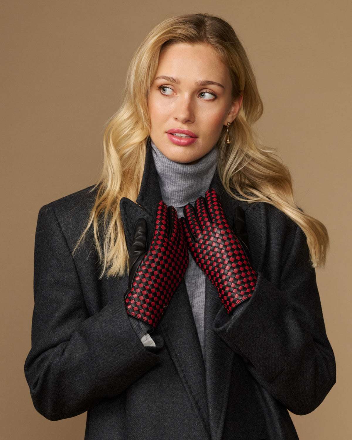 Women's black leather gloves with red-and-black checkered lining, arms crossed