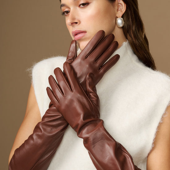 Close-up of women’s brown leather elbow gloves, fingers and cuff detail visible.
