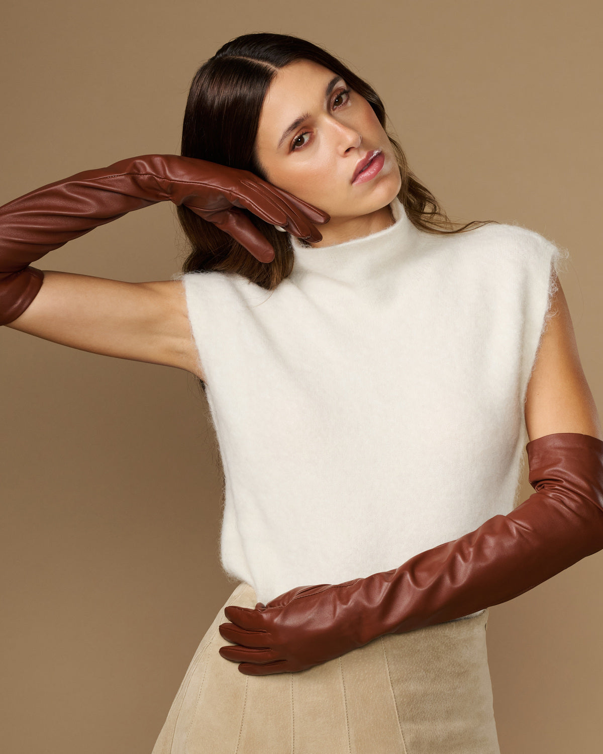 Chestnut brown leather opera gloves with long fingers, posed with arms reaching forward