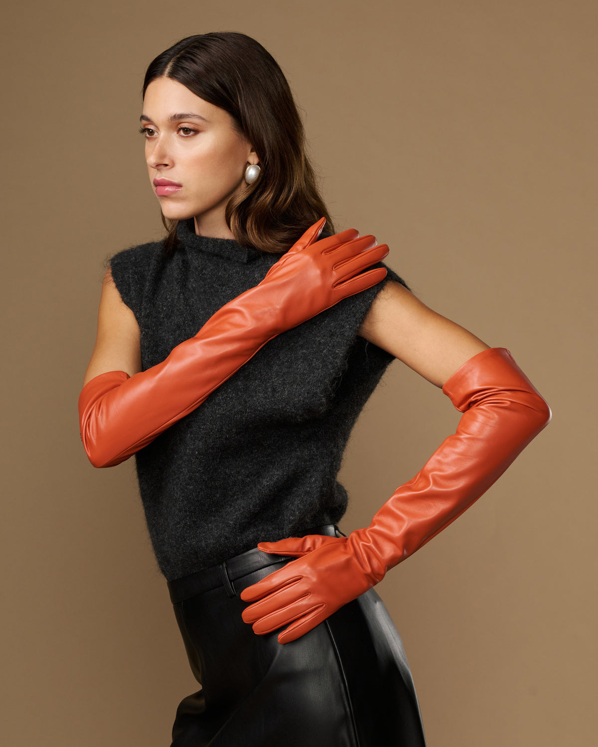 Orange lambskin leather gloves with silk lining and touchscreen tips, hands crossed