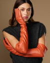 Orange lambskin leather gloves with silk lining; touchscreen tips and seam details on hands
