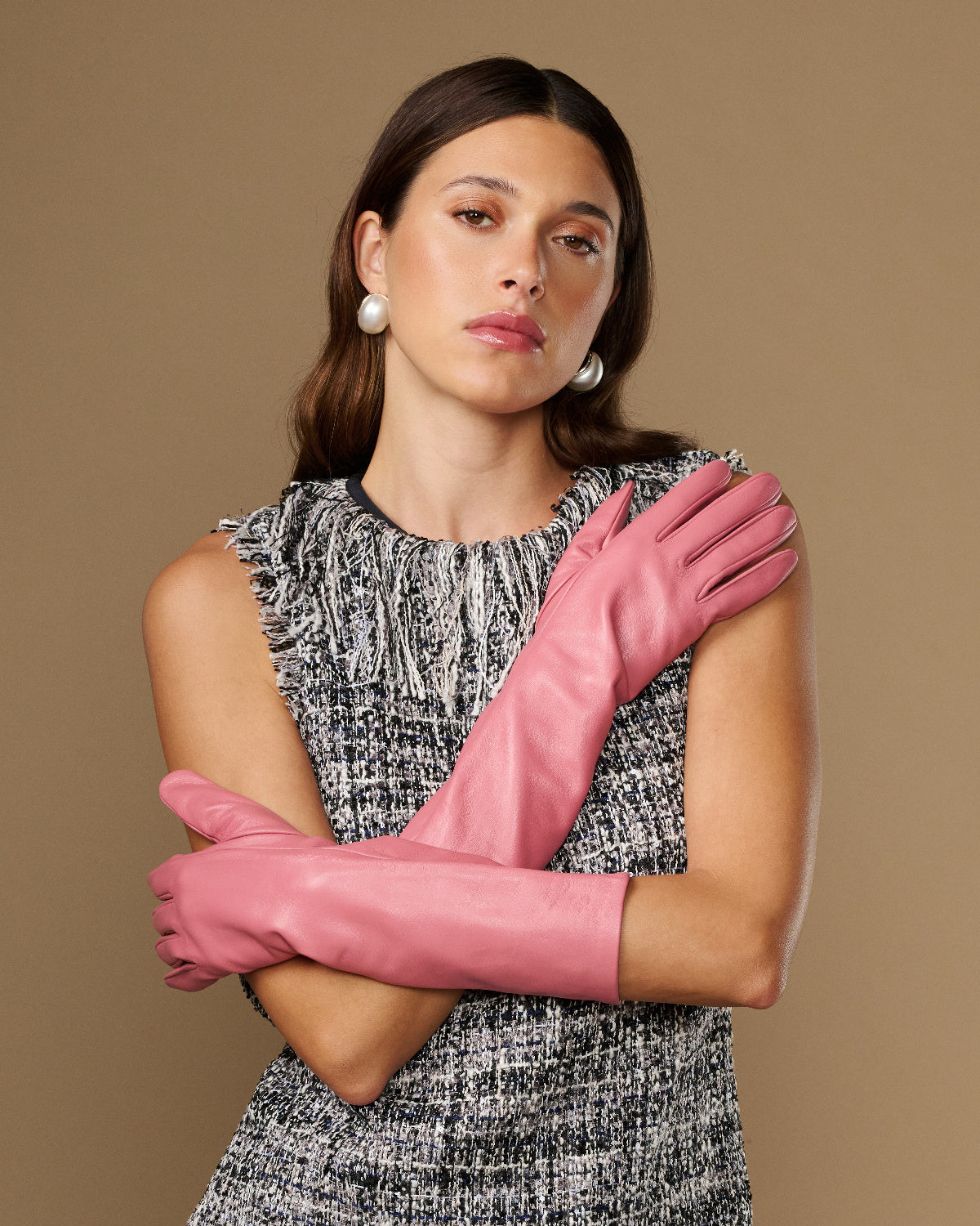 Pink below-elbow leather gloves, smooth fitted style, arms crossed with gloves visible