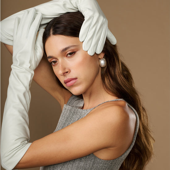 White elbow-length leather gloves worn on raised arms, smooth fingers and cuff