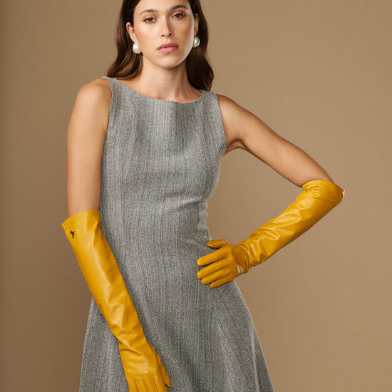 Yellow leather elbow gloves with long cuffs and finger shaping, worn with dress