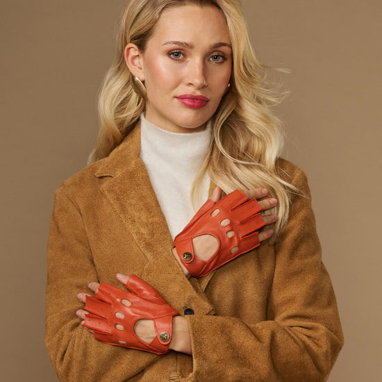 Orange fingerless lambskin driving gloves with open fingers and circular wrist button