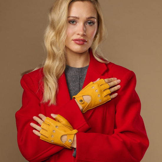Yellow women's fingerless lambskin driving gloves with stitched finger holes and studs