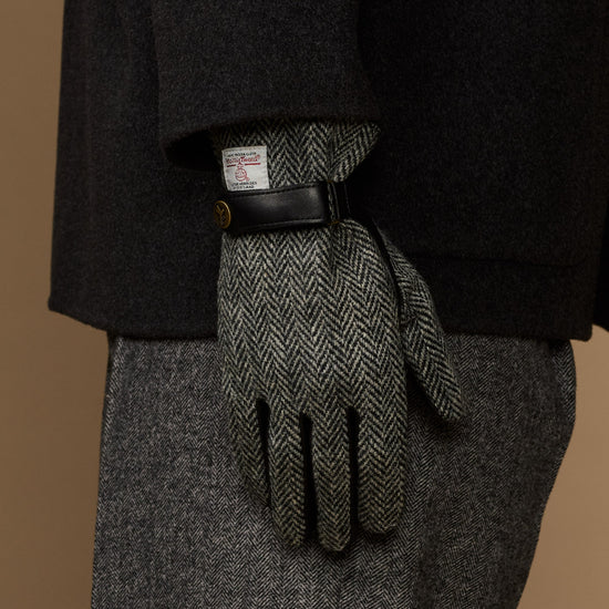 Men's gloves rear view: black leather top and gray herringbone fingers with wrist label.