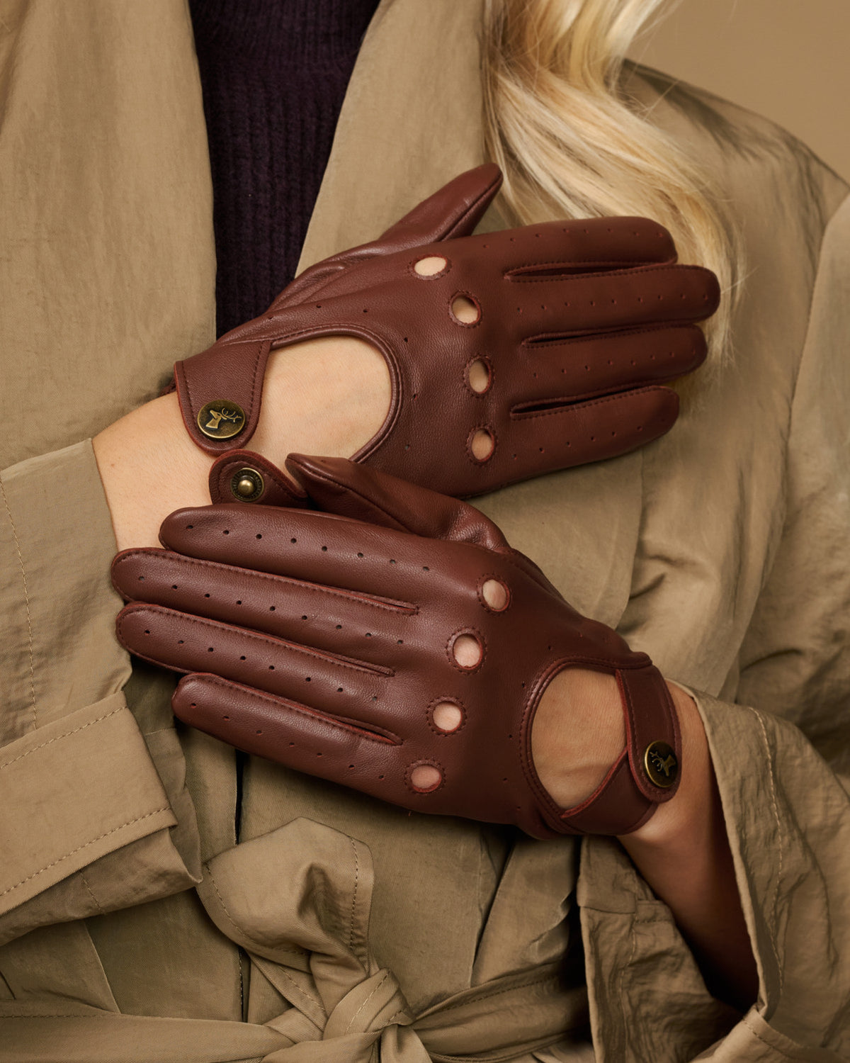 Brown leather gloves with perforated finger panels and decorative button accents