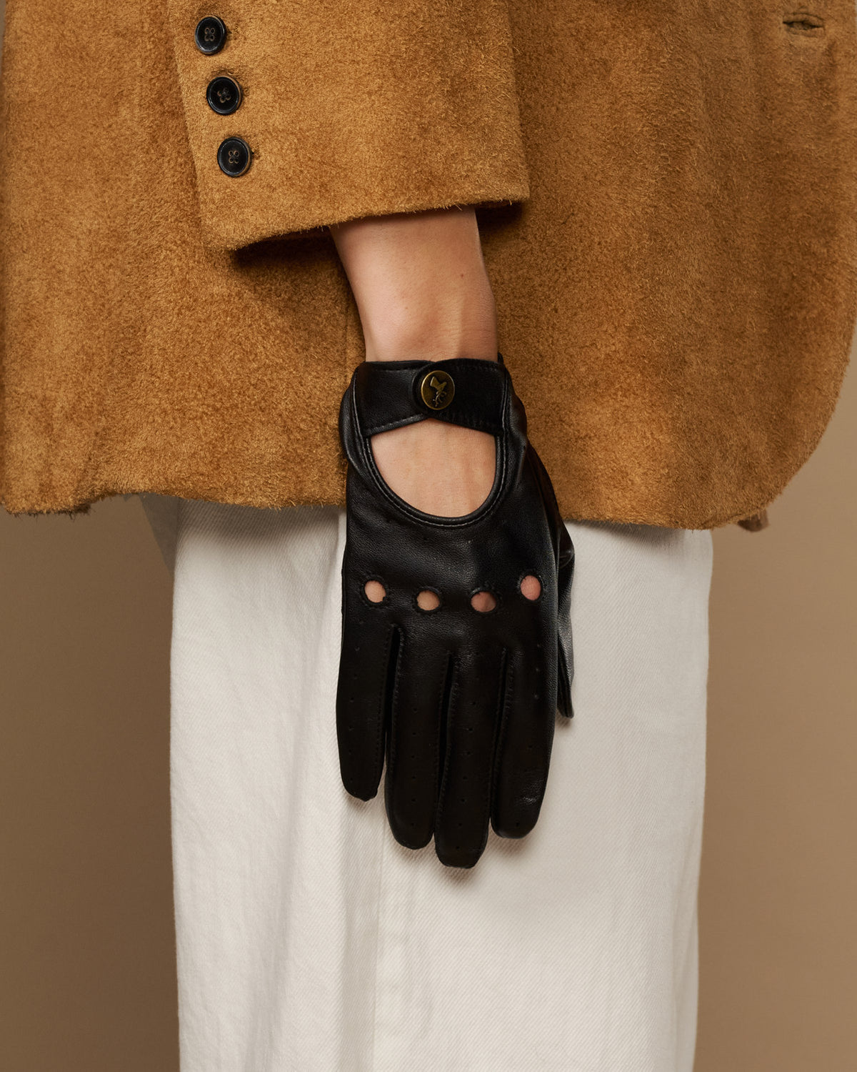 Black leather glove with oval emblem at wrist and studded finger panels.